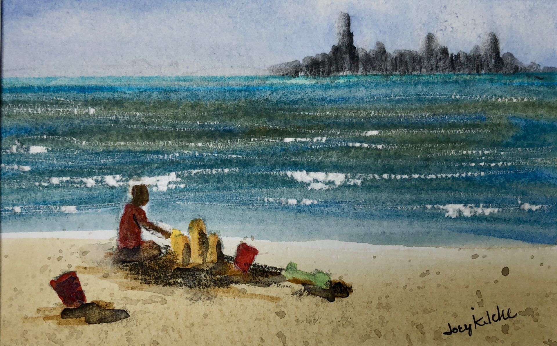 A child makes a sand castle at the beach with the Chicago skyline on the distant shore